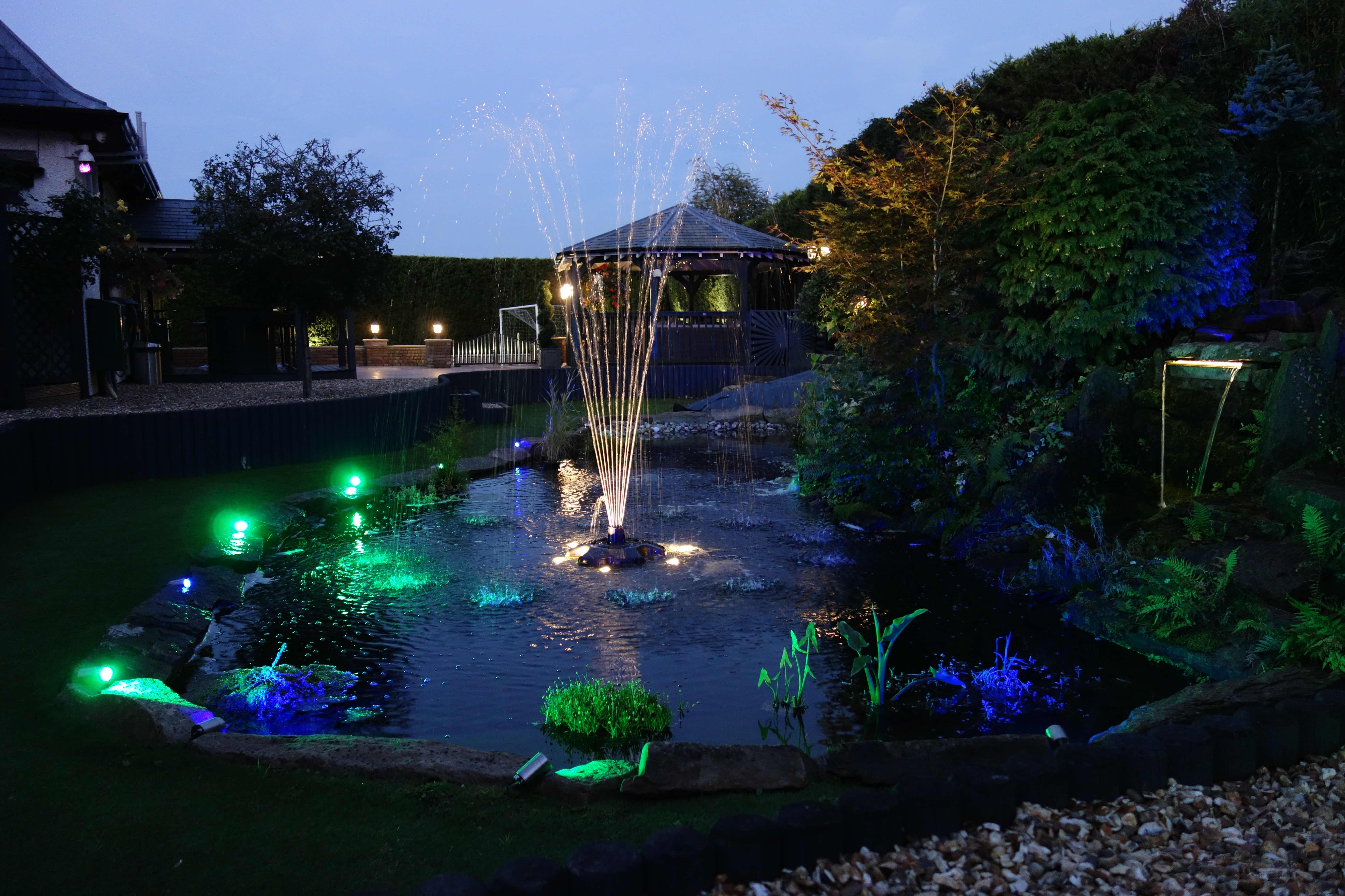 Pond with illuminated fountain and waterfall in Knutsford.