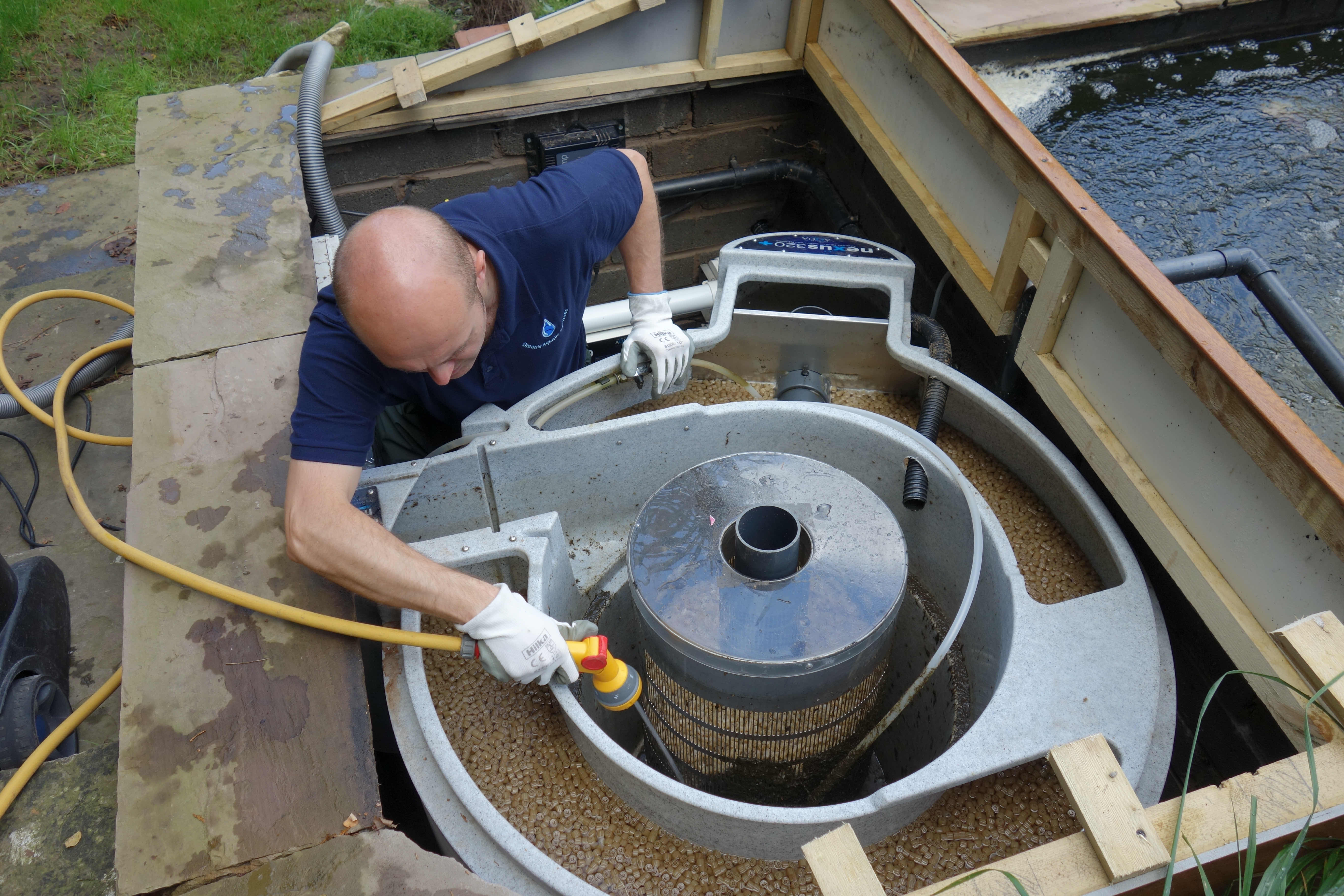 Koi pool specialist cleaning a Nexus filter system, as part of a koi pool maintenance service near Knutsford.