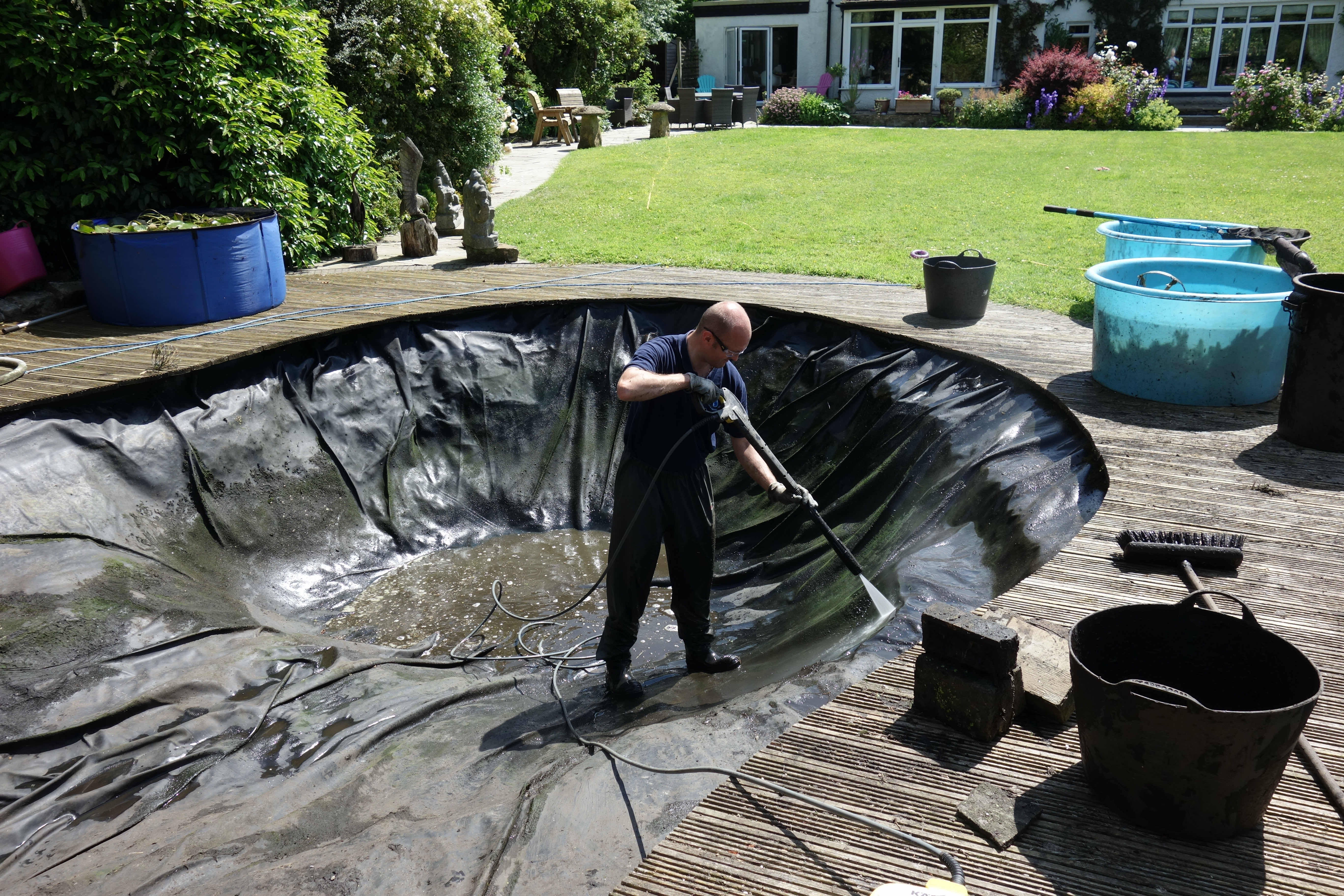 Pond cleaning specialist pressure washing a pond liner, during a pond cleaning service in Clitheroe.